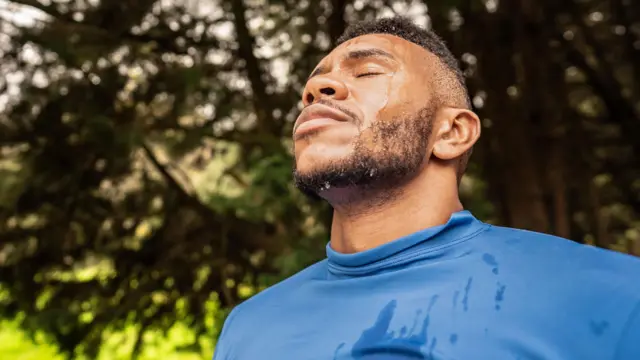 ስፖርት ሰርቶ በፊቱ ላይ ላብ የሚታይ ሰማያዊ ሹራብ የለበሰ ወንድ 