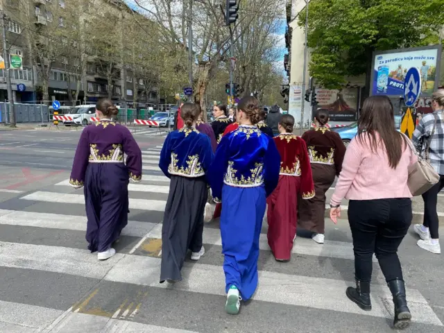 devojke u narodnoj nošnji prelaze ulicu