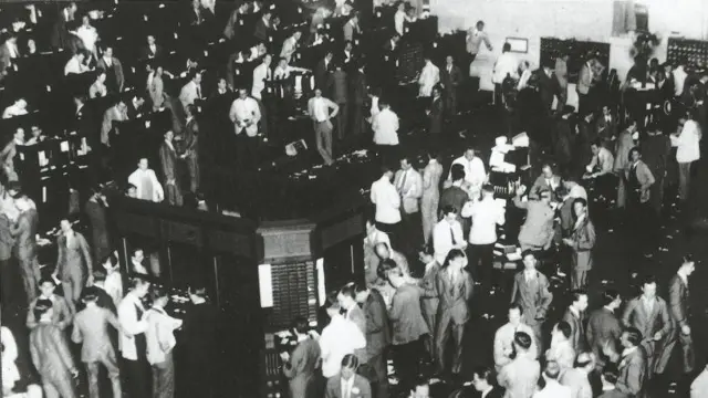 Varias decenas de comisionistas de bolsa están parados con expresión de preocupación.