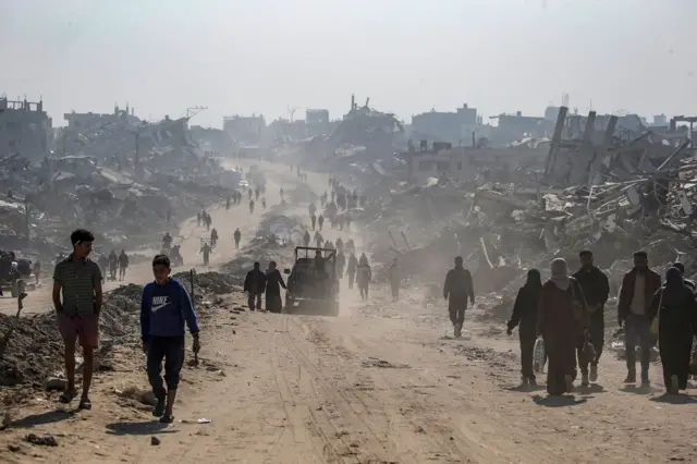 فلسطينيون يسيرون بين أنقاض المباني المدمرة في مخيم جباليا للاجئين