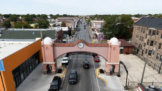 Una vista aérea de la calle 26 y del arco que marca la entrada a Little Village tomada el 9 de septiembre de 2025. En el arco, un letrero lee "Bienvenidos a Little Village". El tráfico es reducido y no hay casi transeúntes.