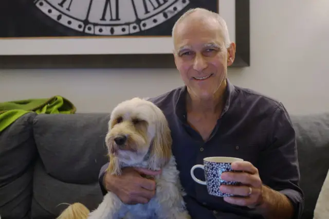 Мунги Бовенди с кружкой в руке и собакой