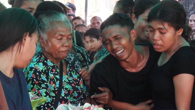Suami Maria, Anselmus Ananius Gonde, tak kuasa menahan tangis saat istrinya dimakamkan pada Jumat (11/04)