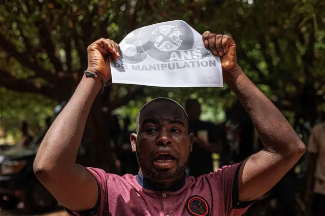 Un manifestant pro-junte tient une banderole alors que des partis politiques opposés protestent contre une dissolution potentielle par les autorités militaires du Mali à Bamako le 3 mai 2025. 