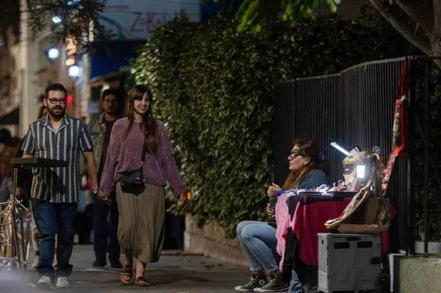 Personas caminan por un barrio de Santiago por la noche.