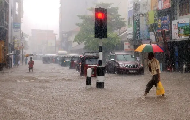 A Sri Lankan man walks along a flooded road in Colombo on May 17, 2010. Several days of heavy rain coupled with strong winds and lightening marked the beginning of the southwest monsoon season. 