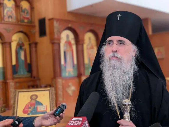 Священник в храме, на заднем плане иконостас