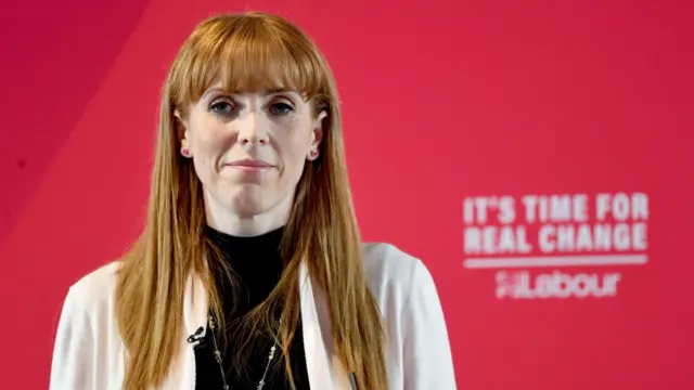 Анджела Рейнер на белом жакете на фоне задника с надписью "Пришло время реальных перемен - Лейбористы"