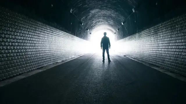 Homem em túnel com luz ao fundo