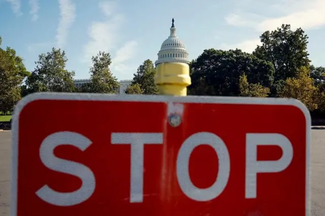 تصویری از کنگره امریکا که جلوی ان یک تابلو ایست راهنمایی و رانندگی برابر لنز دوربین قرار دارد