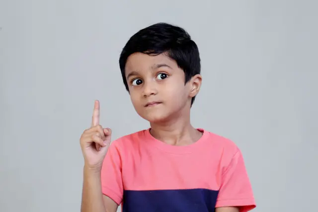 Little boy showing index finger with funny expression - stock photo Little boy showing index finger with funny expression