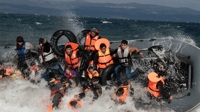 Refugiados que llegan a la isla de Lesbos caen de un barco que vuelca al aterrizar en mares agitados procedentes de Turquía