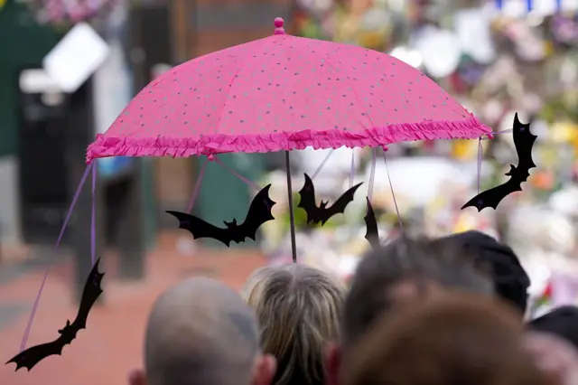 Розовый зонтик, к которому ленточками привязаны летучие мыши.