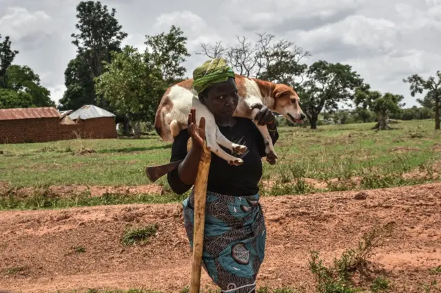 Une femme porte son chien sur l'épaule alors qu'elle marche dans la banlieue de Mangu, près de Jos, dans l'État du Plateau au Nigeria, le 20 mai 2023.