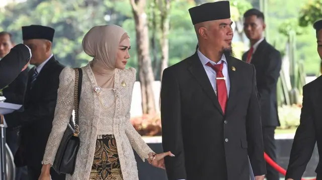 Pasangan artis sekaligus anggota DPR terpilih masa bakti 2024-2029 dari Partai Gerindra Ahmad Dhani Prasetya (kanan) dan Mulan Jameela (kiri) tiba di Gedung Nusantara untuk mengikuti pelantikan di Kompleks Parlemen, Senayan, Jakarta, Selasa (1/10/2024).