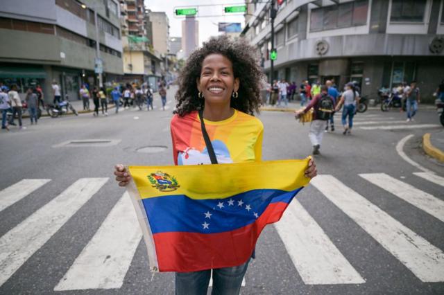Simpatizante de Nicolás Maduro en la calle con una bandera de Venezuela.