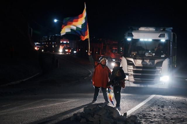 Un hombre ondea la bandera de las comunidades indígenas mientras detiene el tráfico en un bloqueo de carretera en Purmamarca, junio 22 de 2023