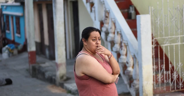 Una mujer, con gesto de preocupación en mitad de una calle. 