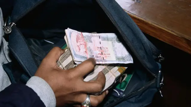 झोलाबाट पैसाको बिटो निकाल्दै मानिस