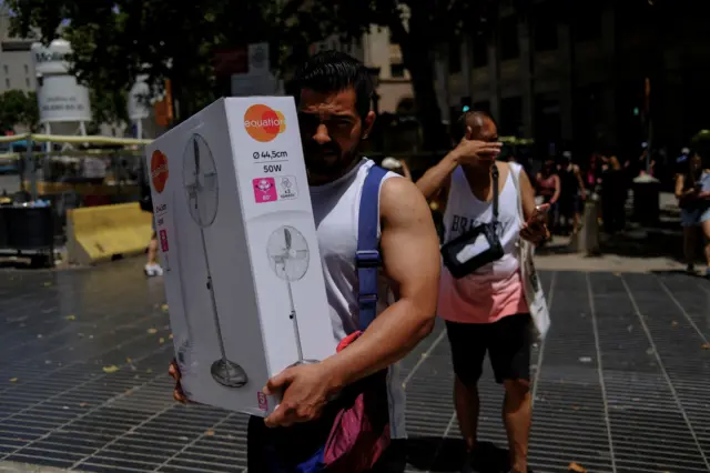 Egy férfi frissen vásárolt ventilátort visz Barcelonában, Spanyolországban 2026. június 21-én.