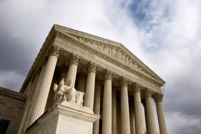 منظر خارجي لمدخل مبنى المحكمة العليا وما تحيط به من أعمدة مزخرفة خارجية وعلى الواجهة أيضا تماثيل منقوشة بالجدار الأعلى وهناك على الجانب الأيسر يظهر أحد التمثالين الموضوعين عند العتبة ليجسدا سيدة جالسة ممسكة بالدستور باليسرى وتمثال سيدة العدالة معصبة العينين في اليد اليمنى. المنحوتتان ترمزان لسير العدالة التداولية بحسب صانعهما جيمس إيرل فريزر وتم تركيبهما عام 1935، بعد شهر من افتتاح المبنى.