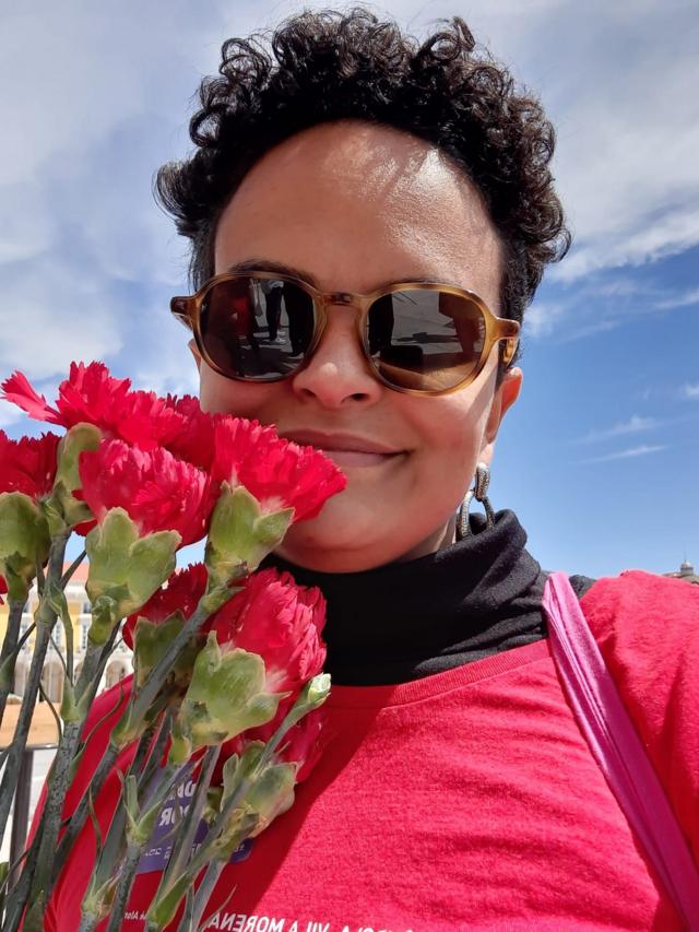 Hérika Nogueira sorrindo enquanto segura buquê de flores