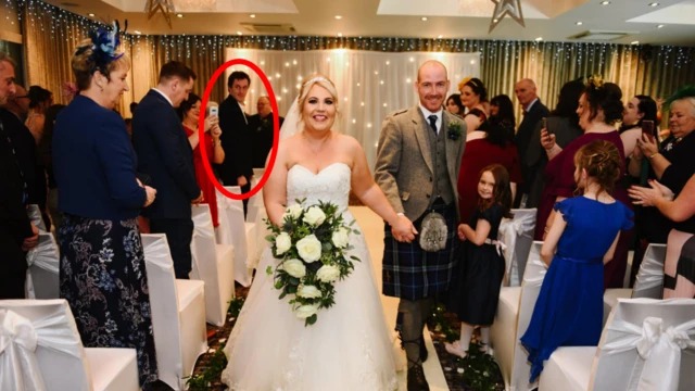 A noiva e o noivo caminham sorrindo de volta pelo corredor após a cerimônia. Muitos convidados aplaudem. Andrew Hillhouse aparece ao fundo entre os presentes, destacado por um círculo vermelho.