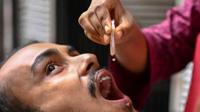 ২০২২ সালের ৪ অগাস্ট ঢাকায় টিকাদান কর্মসূচি চলাকালে একজন স্বাস্থ্যকর্মীর কাছ থেকে মুখে খাওয়ার কলেরার টিকা গ্রহণ করছেন এক ব্যক্তি।
