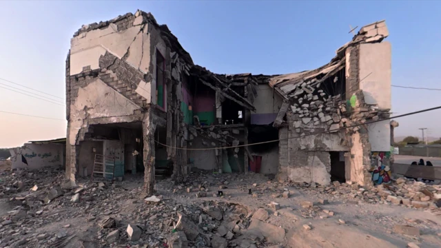 Minab'daki Şahereh Tayyebeh İlkokulu'ndan geriye kalan bölüm. Ağır hasar görmüş iki katlı bir bina olup, duvarlarının bazı bölümleri eksik ve beton parçaları binadan sarkmaktadır. Bina, molozlarla dolu düz bir alanla çevrilidir.