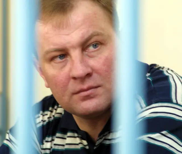 Мужчина в гражданской одежде за решеткой на скамье подсудимых