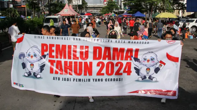 Relawan berjalan sambil membentangkan spanduk saat sosialisasi Pemilu Damai 2024 di area pelaksanaan Hari Bebas Kendaraan Bermotor (HBKB) di Makassar, Sulawesi Selatan, Minggu (28/1).
