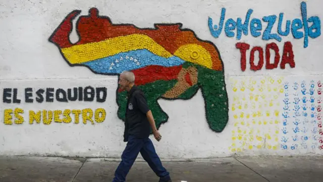 Un hombre pasa por un mural del mapa de Venezuela que incluye el Esequibo y al lado se lee: el Esequibo es nuestro.