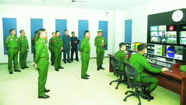 ကွန်ပျူတာသုံးနေတဲ့ စစ်သား၂ ဦးကို နောက်မှာ ရပ်ကြည့်နေကြတဲ့ ဗိုလ်ချုပ်ကြီးရဲဝင်းဦးနဲ့ စစ်ဗိုလ်ချုပ်တွေ