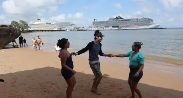 Люди на берегу, на заднем плане в море видны круизные лайнеры