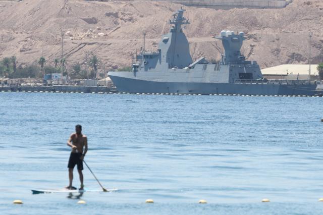 Um homem rema na frente de uma corveta Sa'ar classe 6 de fabricação alemã da marinha israelense atracada na cidade portuária de Eilat, no Mar Vermelho, em 16 de abril de 2024