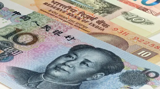 Banknotes from various countries including India and China, with a Chinese yuan note featuring former leader Mao Zedong in the foreground.