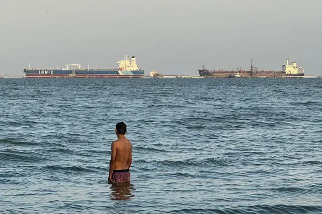 Un hombre entra en el agua con el buque petrolero Ionic Anax y el buque cisterna para petróleo y productos químicos Stef atracados al fondo, en el lago de Maracaibo, en Maracaibo, Venezuela, el 1 de marzo de 2026. Venezuela fue en el pasado un importante proveedor de crudo para EE.UU. y posee las mayores reservas probadas del mundo, con más de 303.000 millones de barriles, según el cartel petrolero mundial de la OPEP. (Foto de Margioni BERMÚDEZ / AFP vía Getty Images)