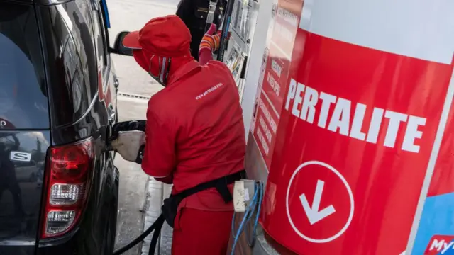 Seorang pekerja mengisi ulang mobil pelanggan dengan bahan bakar Pertalite