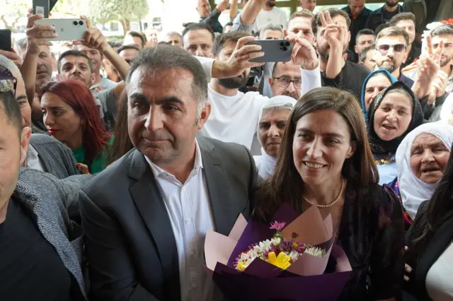 Görevden alınan eski belediye eş başkanı Mehmet Demir (solda) ve Songül Korkmaz genç belediye başkanını belediye binası kapısında çiçekle karşıladılar