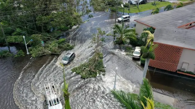 Fort Myers'ta sel suları altında kalan bir alanı geçmeye çalışan araçlar. 