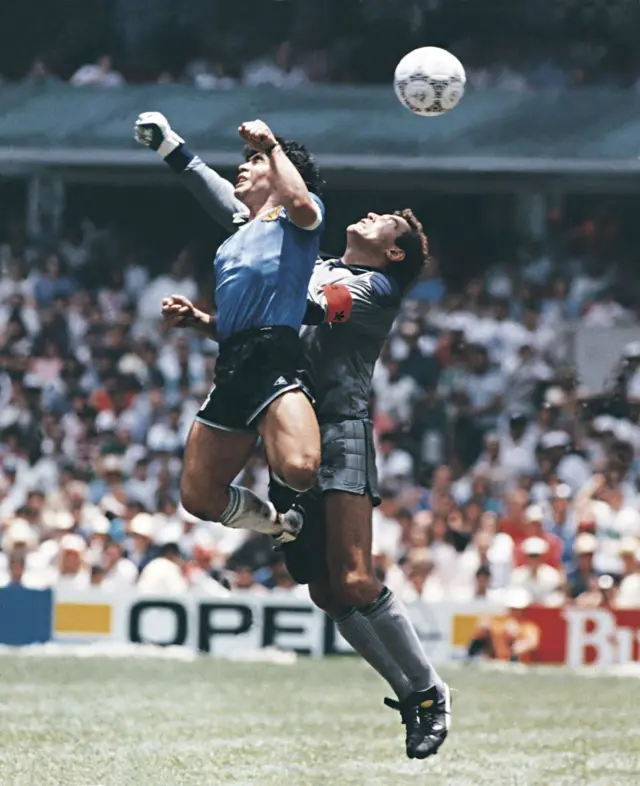 Diego Maradona, da Argentina, usa a mão para marcar o primeiro gol de sua equipe durante uma partida das quartas de final da Copa do Mundo FIFA de 1986 entre Argentina e Inglaterra, no Estádio Azteca, em 22 de junho de 1986. Maradona afirmou posteriormente que o gol foi marcado pela "Mão de Deus".
