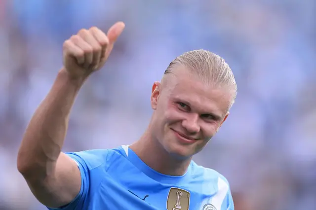 Erling Haaland acenando para as pessoas e sorrindo