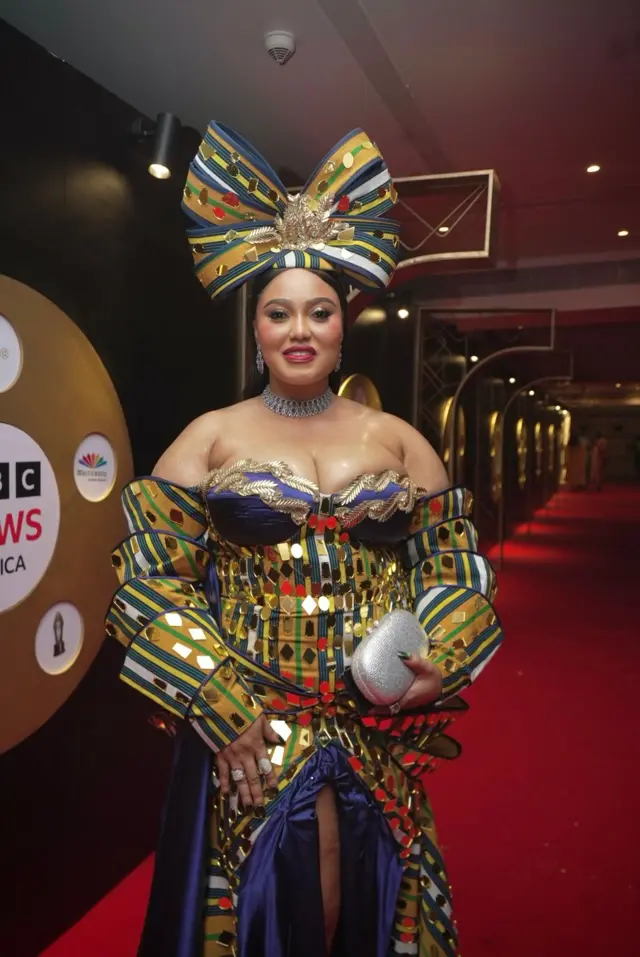 Icyamamare muri reality TV OJ Posharella yagaragaye ku i tapis itukura afite umutako munini ufite nk'ipfundo ku mutwe, yambaye n'umwambaro w'amabara atandukanye yihangiye ubwe.