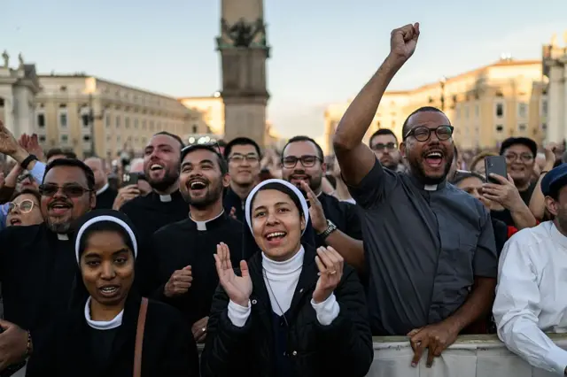 Los miembros del clero reaccionan al ver al recién elegido Papa León XIV, Robert Prevost, haciendo su primera aparición en el balcón de la logia central de la Basílica de San Pedro por primera vez, después de que los cardenales finalizaran el cónclave, en El Vaticano, el 8 de mayo de 2025. (Foto de JEFF PACHOUD/AFP a través de Getty Images)