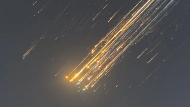 空中分解したスペースXの宇宙船がオレンジ色に光り落下する様子。マーカス・ハワースさん撮影動画より(16日、タークス・カイコス諸島)