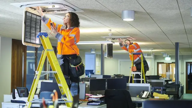 Trabajadores instalando aires acondicionados.