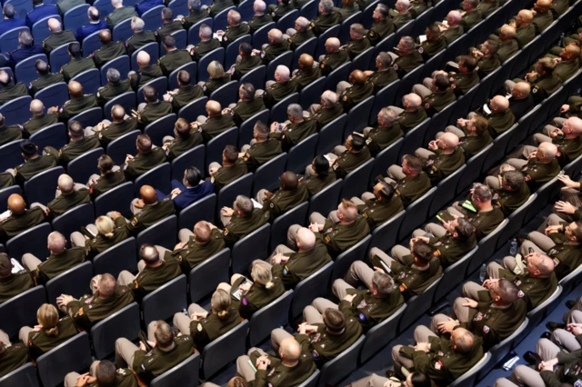 Jefes militares de EE.UU. sentados en un auditorio escuchan el discurso de Trump