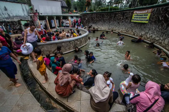 Orang-orang berenang dan berendam di kolam air panas di kawasan wisata Pacet, Mojokerto, Provinsi Jawa Timur.
