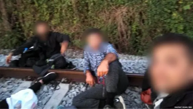 Three migrants pose in a selfie on some railtracks (faces are obscured to prevent identification)