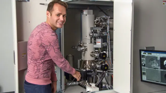 Pierre Haenecour ao lado de um dos microscópios eletrônicos que permitiram analisar o grão de poeira a nível atômico